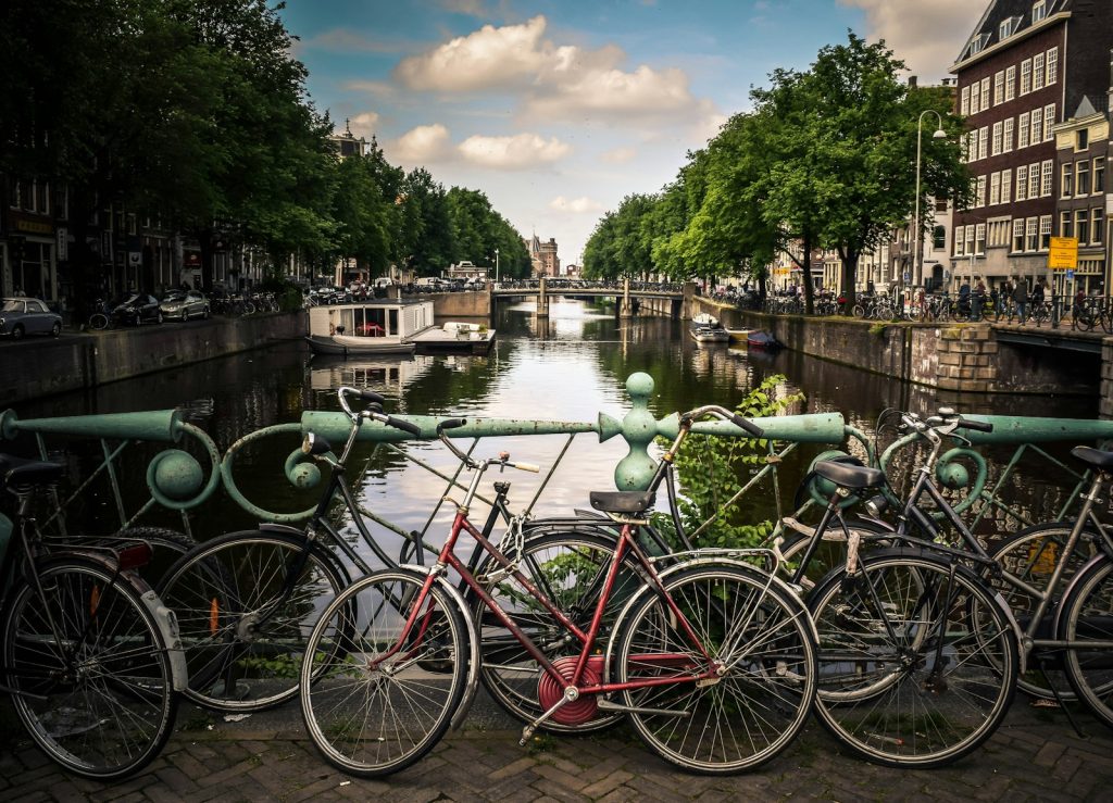 assorted-color bicycles park beside blue rails near river Amsterdam