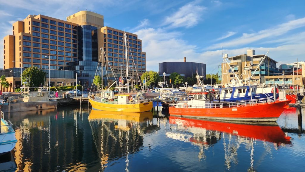 several boats are docked in a harbor in front of a large building Hobart
